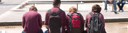 Group of boys sitting on a bench with their backs to the camera