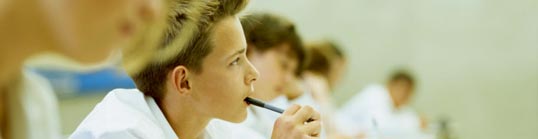 A schoolboy thinking, holding a pen in his mouth